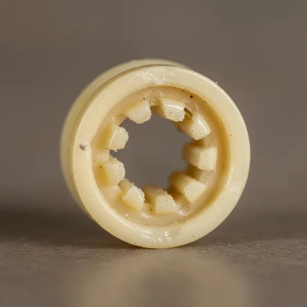Close-up of a damaged, stripped plastic drive coupling from a coffee grinder.